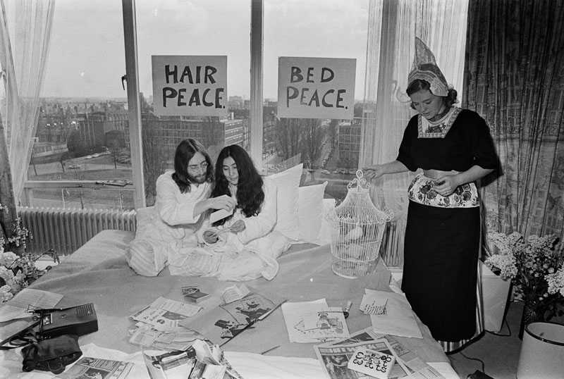 Dutch lady wearing the traditional costume of Volendam offers a dove of peace to Yoko & John : Amsterdam Hilton Hotel 1969 ( Photo: Ruud Hoff)