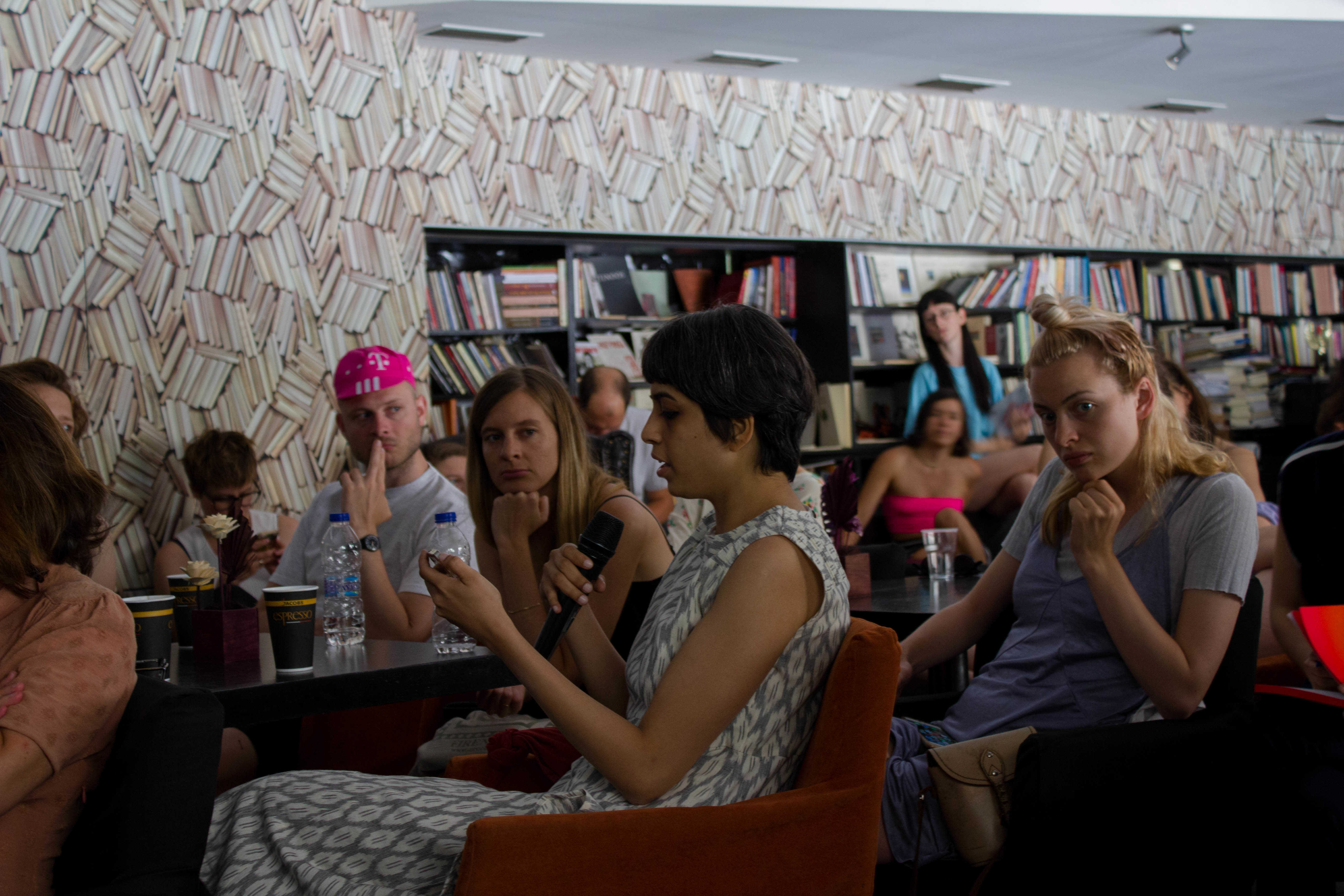 COOP SUMMIT 2018. Final presentation by the ‘Proximity Aesthetics’ study group at the Polis Art Cafe in Athens on June 2. In the picture: Vinita Gatne reading from the Proximity Aesthetics website on her phone. Photo: Silvia Ulloa for DAI Roaming Academy.