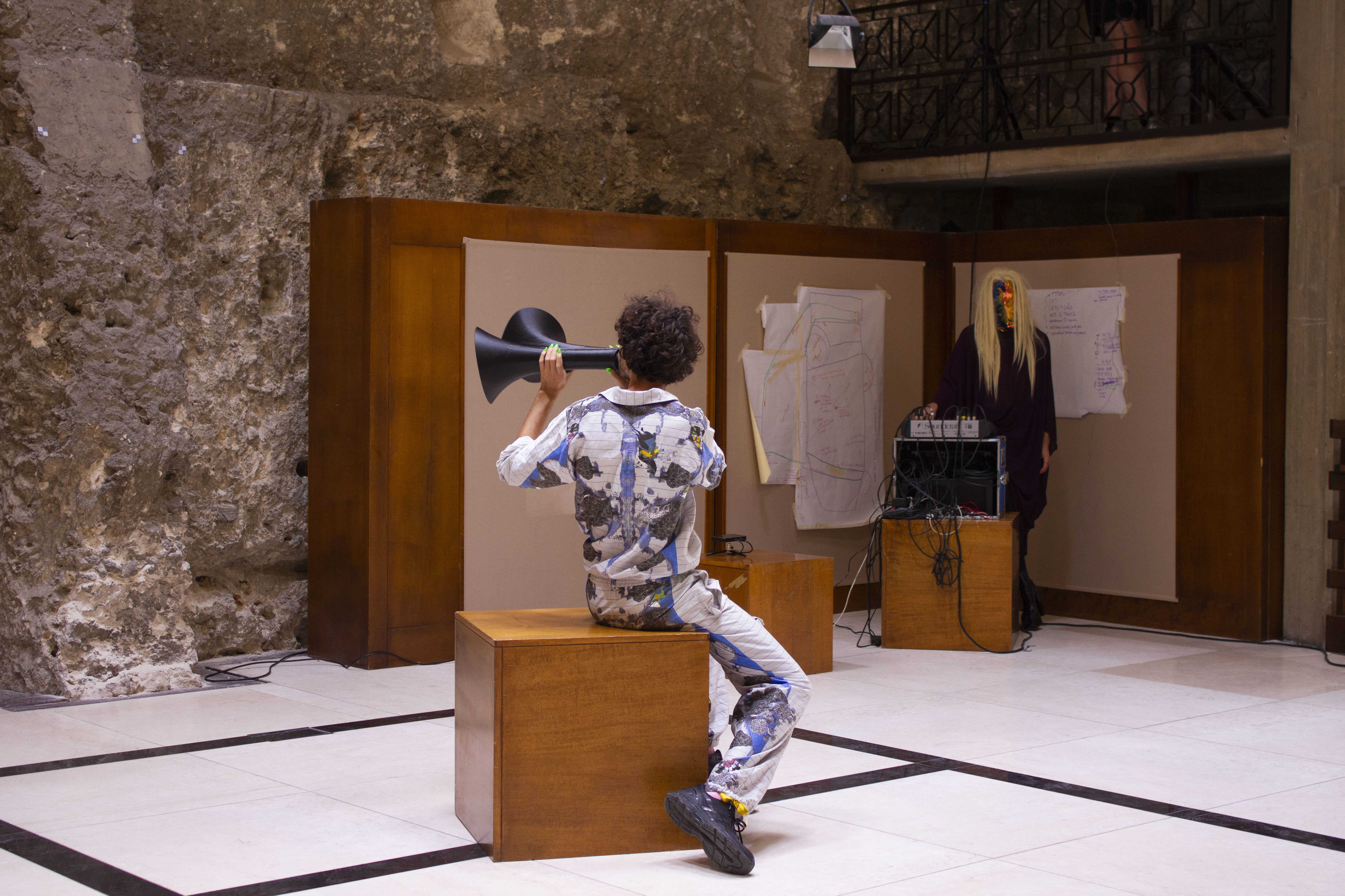 Scene from: "Untitled (Orificially Yours) , the ninth act of the COOP study group “The Immemorial Body: Betraying Carmelo Bene in 9 Acts” . Cagliari, June 29, 2019. Location: Sala Mostre Temporanee, Cittadella dei Musei. Photo: Silvia Ulloa