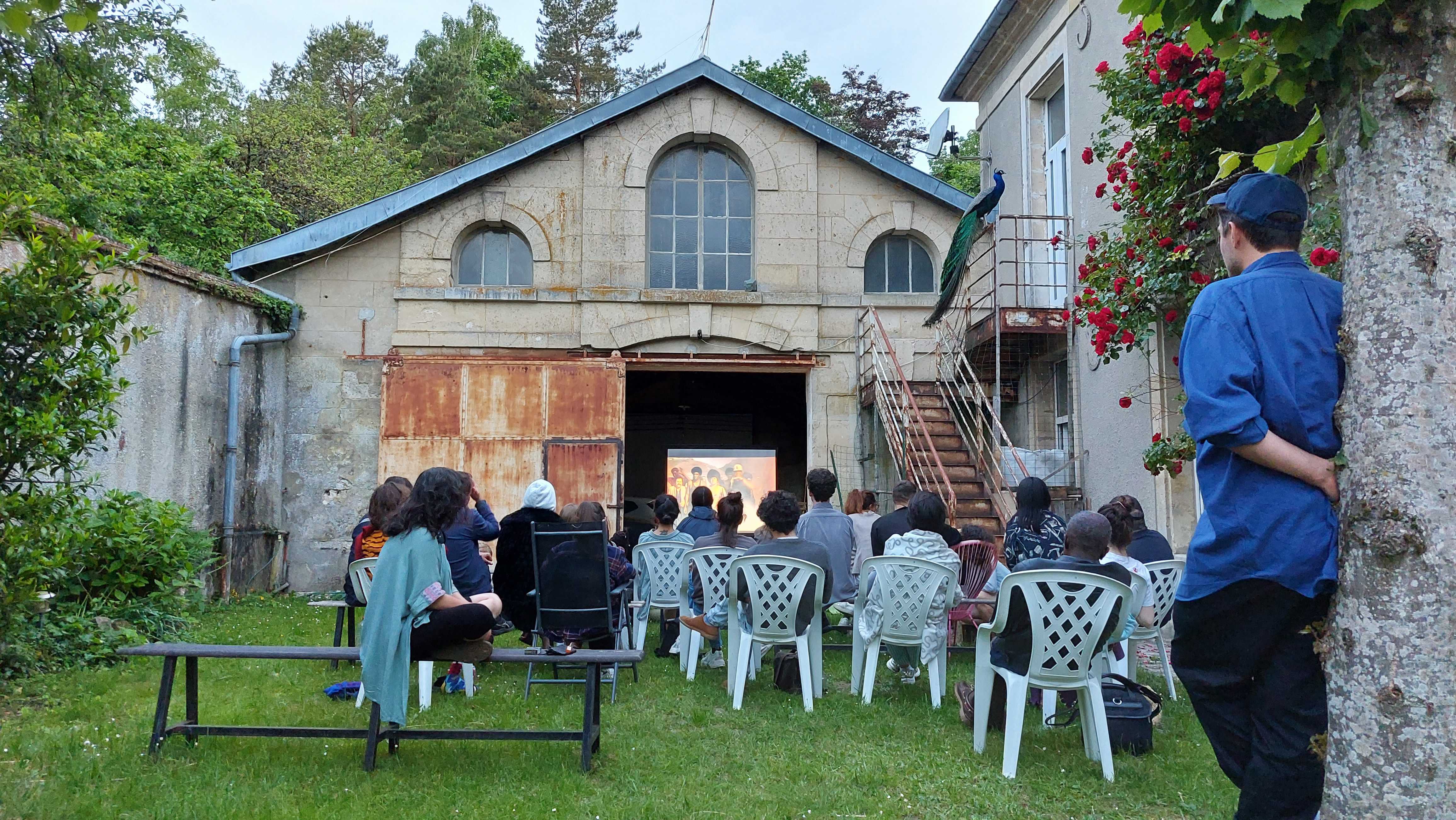 Outdoor screening of John Akomfrah's The Last Angel of History (1996) with introduction by Ana Teixeira Pinto, COOP study group: ReSituating and ReCalibrating Hostipitality hosting HTDTWT tutor. PAF, June 2021. Photo credits: Nikos Doulos